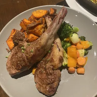 Lamb chops with roasted sweet potatoes and mixed vegetables.