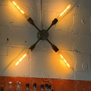 a clock made of four lights and bottles of liquor