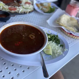 a bowl of chili soup and a plate of tortillas