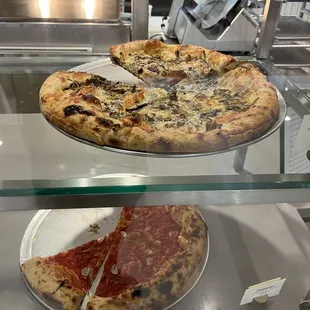 two pizzas in a display case
