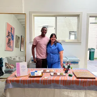 a man and woman standing in front of a table