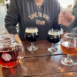 a woman sitting at a table with four glasses of beer