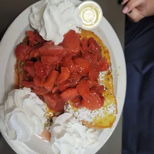 a plate of french toast with strawberries and whipped cream
