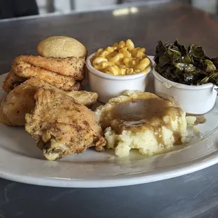 a plate of chicken, mashed potatoes, corn, and gravy