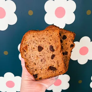 a hand holding a piece of chocolate chip bread