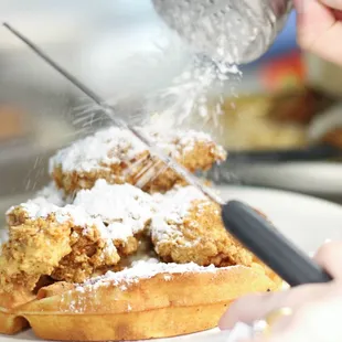 a waffle being sprinkled with powdered sugar