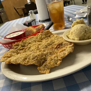 Huge chicken fried steak with gravy on the side.