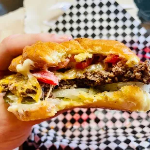 a hand holding a cheeseburger