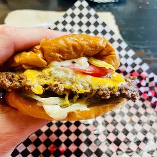 a hand holding a cheeseburger