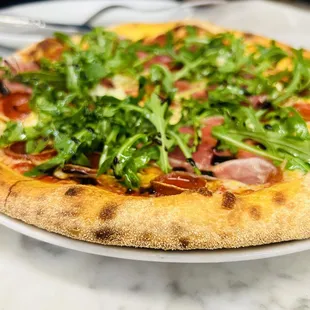 a pizza with greens on top