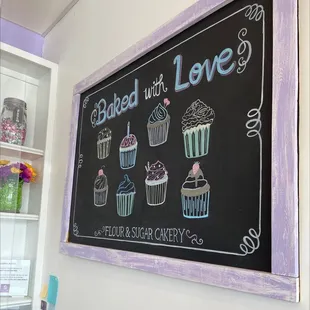 a chalkboard with a variety of cupcakes