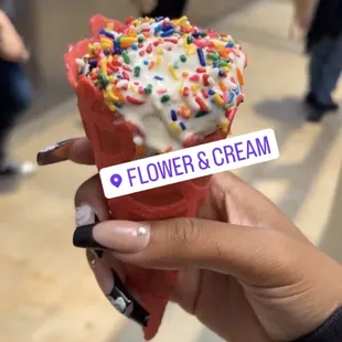 a hand holding a cone of ice cream with sprinkles