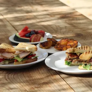 three plates of sandwiches on a picnic table