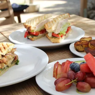 three plates of sandwiches and fruit