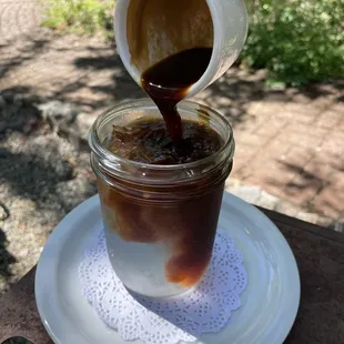 a person pouring coffee into a jar