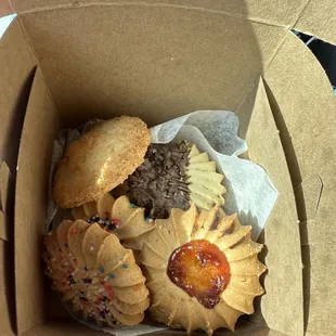 In the box - left to right, rainbow sprinkles, coconut, chocolate dipped with chocolate sprinkles, and apricot dot filled cookie.