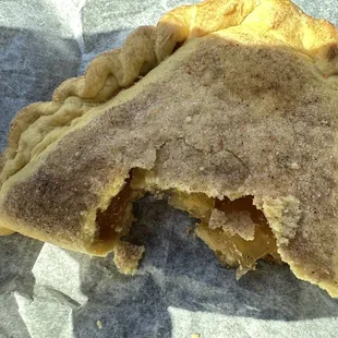 Apple filled pastry with cinnamon sugar sprinkled on top. A crunchy crust around edges and a bit firmer in the middle.