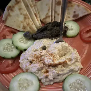 a plate of food with pita chips, cucumbers and tomatoes