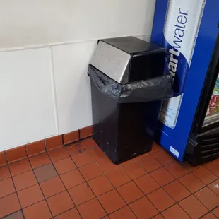 a soda machine and a trash can