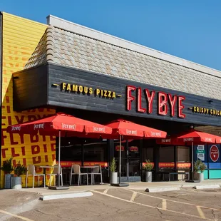 the outside of a restaurant with red umbrellas