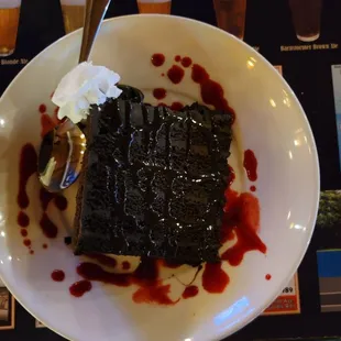 Chocolate Cake with Raspberry sprinkled around it and a dollop of whipped cream on one corner. Served at Oak Harbor Flyer&apos;s