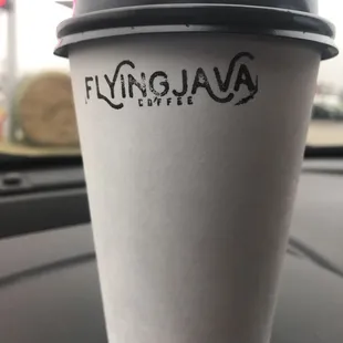 a cup of coffee on the dashboard of a car