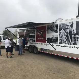 ows a group of people standing in front of a food truck