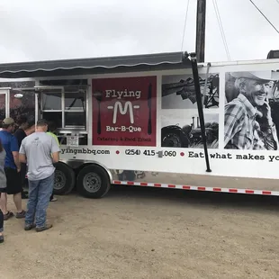 ows a group of people standing in front of a food truck