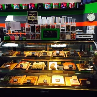 Homemade fudge in the glass display, popcorn to the right and popcorn tins above.