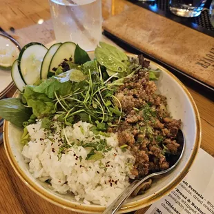 a bowl of rice, cucumber, and meat