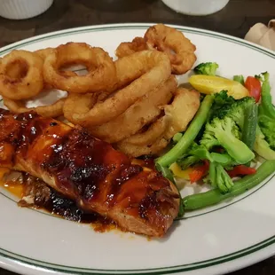 Grilled salmon with honey bbq sauce, onion rings, and vegetables