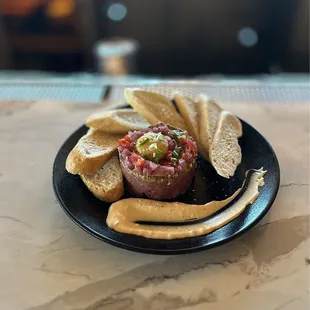 PICANHA TARTARE*: fresh egg, ground mustard, garlic chips, pickled onions, capers, mixed olives, chimichurri w/crispy toasts | $11
