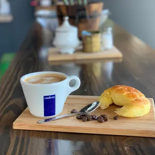 a cup of coffee and a pastry on a cutting board