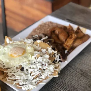 Desayuno Fonda, crunchy and spicy hot chilaquiles, grilled beef, fried beans, 1 egg and chicharrón (pork skin) in salsa