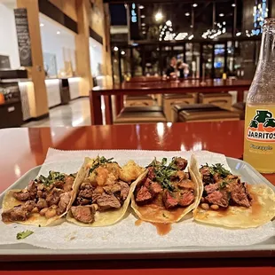 a plate of tacos and a bottle of beer