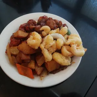 A mixture of different chicken dishes, potatoes, and shrimp.