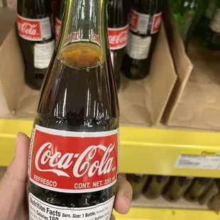 a hand holding a bottle of coca cola