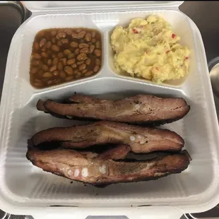 shows ribs, beans, and mashed potatoes in a styrofoam container