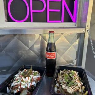 two trays of food and a bottle of coke