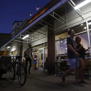 a man and a woman walking past a restaurant