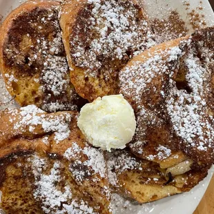 a plate of french toast with butter and powdered sugar