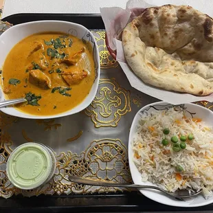 a plate of food with rice, bread, and a bowl of soup
