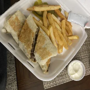 a sandwich and french fries in a styrofoam container
