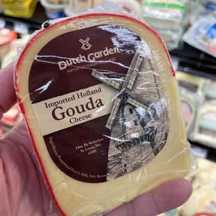 a hand holding a piece of gouda cheese