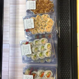 a variety of sushi in plastic containers