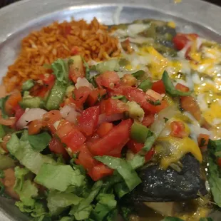 Blue corn tortilla chicken enchilada with green chile, cheese, lettuce, tomatoes, Spanish rice, and beans