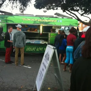 a crowd of people standing around a food truck