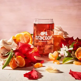 a glass of orange juice surrounded by flowers