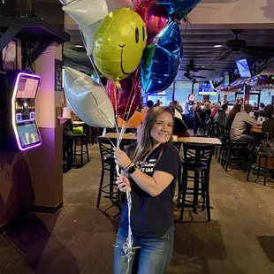a woman holding a bunch of balloons