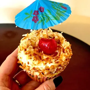 a hand holding a cupcake with a blue umbrella